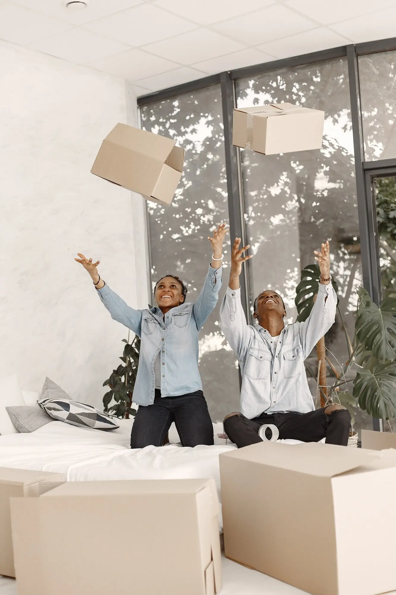 Ein junges afroamerikanisches Paar zieht gemeinsam mit Pappkartons in ein neues Zuhause ein.